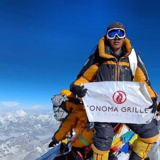 Climber waves Sonoma Grille flag at top of Mount Everest